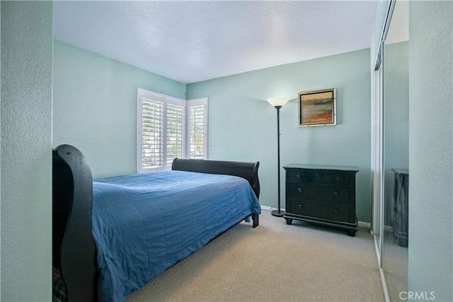 bedroom featuring light carpet and baseboards