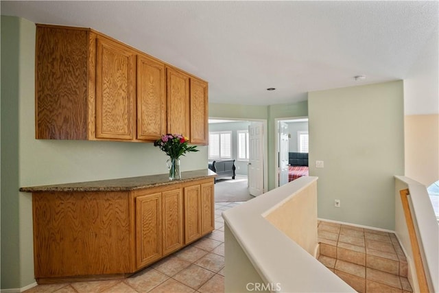 hall featuring light tile patterned floors and baseboards