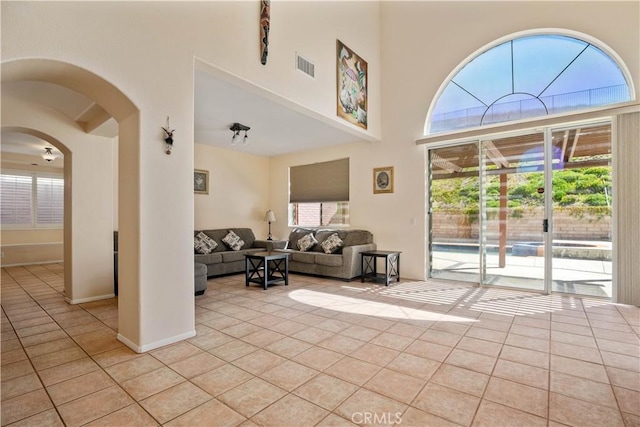 entryway featuring light tile patterned floors, visible vents, a healthy amount of sunlight, and a high ceiling