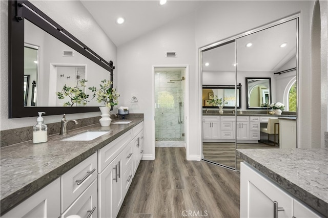 full bath with visible vents, lofted ceiling, a stall shower, wood finished floors, and a sink