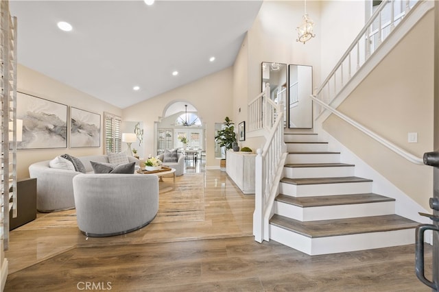 living area with stairs, recessed lighting, a high ceiling, wood finished floors, and a notable chandelier