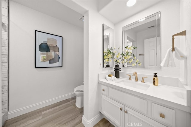 bathroom featuring vanity, toilet, wood finished floors, and baseboards