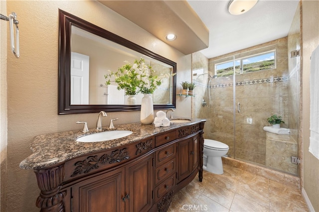 bathroom with a sink, toilet, a stall shower, and double vanity