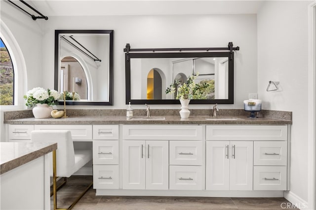 bathroom with double vanity, wood finished floors, and a sink