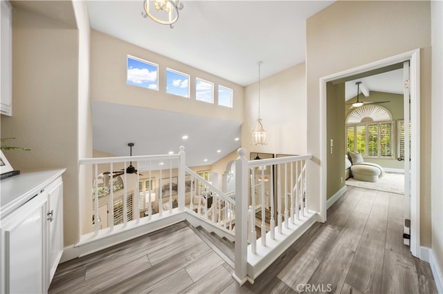 hall featuring an upstairs landing, high vaulted ceiling, baseboards, and wood finished floors