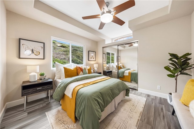 bedroom with light wood finished floors, ceiling fan, a closet, and baseboards