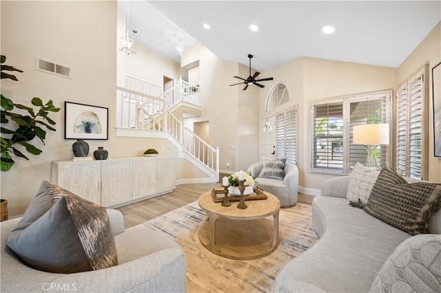 living area with stairs, wood finished floors, a ceiling fan, and visible vents