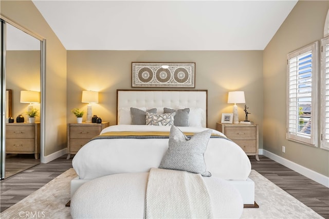 bedroom with baseboards, lofted ceiling, a closet, and wood finished floors