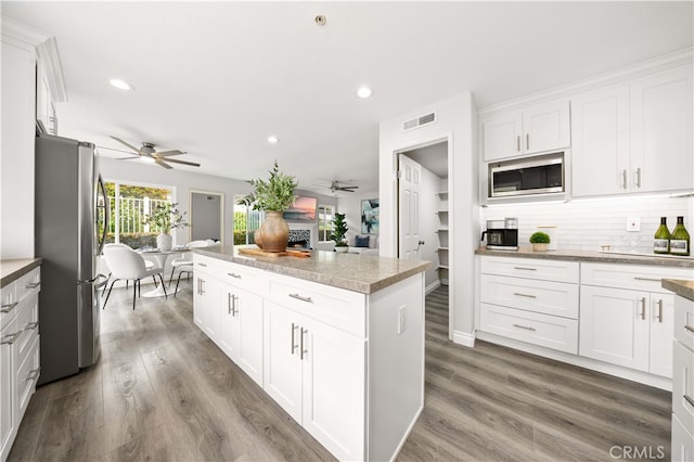 kitchen with a center island, decorative backsplash, stainless steel appliances, and ceiling fan