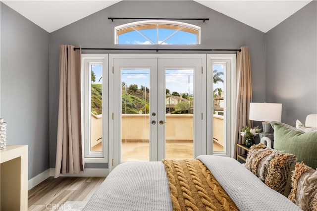 bedroom with access to exterior, wood finished floors, french doors, and vaulted ceiling