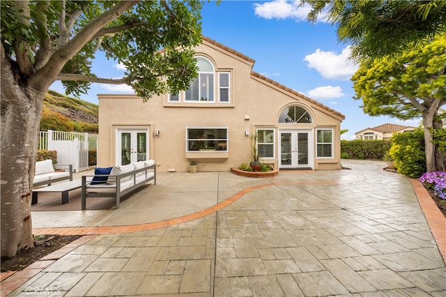 rear view of house with a patio area, french doors, and stucco siding