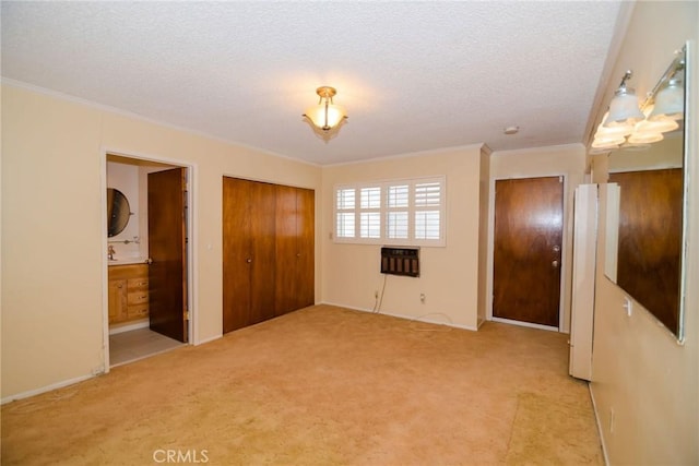 unfurnished bedroom featuring ornamental molding, carpet floors, ensuite bathroom, heating unit, and a textured ceiling