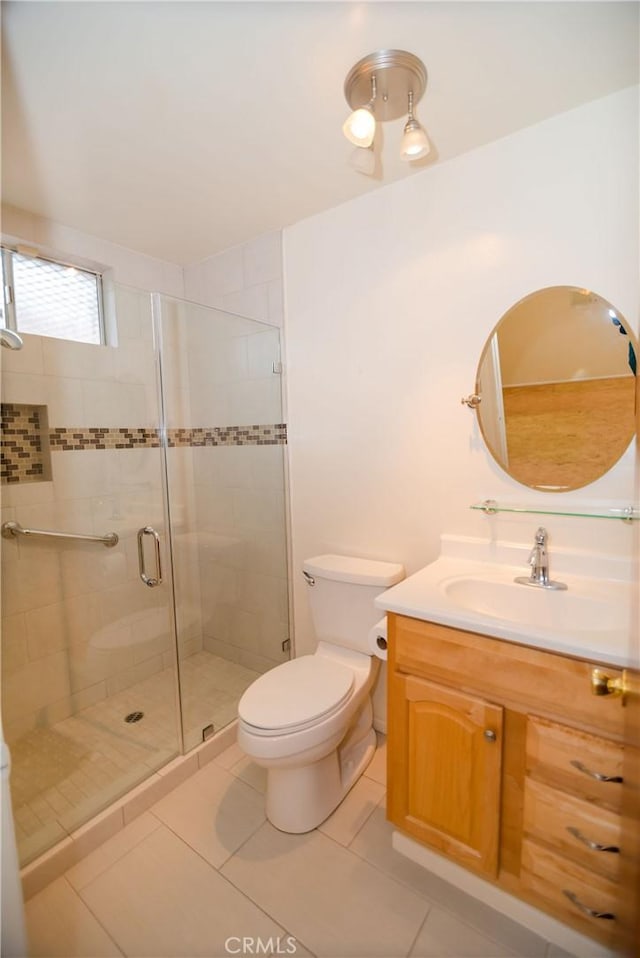 bathroom featuring tile patterned floors, a shower stall, toilet, and vanity