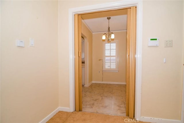 corridor featuring a chandelier, crown molding, and baseboards