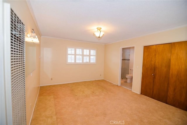 unfurnished bedroom featuring a closet, light colored carpet, connected bathroom, and crown molding