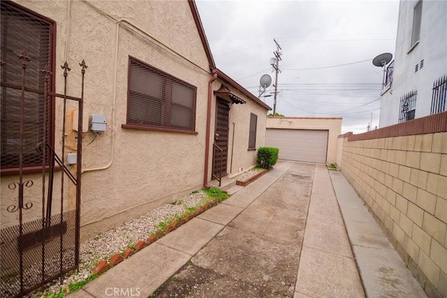 view of home's exterior featuring an outbuilding, fence, a detached garage, and stucco siding