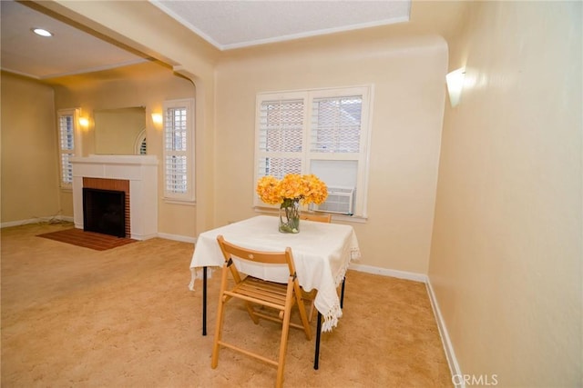 carpeted dining area with crown molding, a brick fireplace, recessed lighting, and baseboards