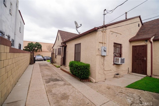 view of home's exterior with cooling unit, fence, and stucco siding