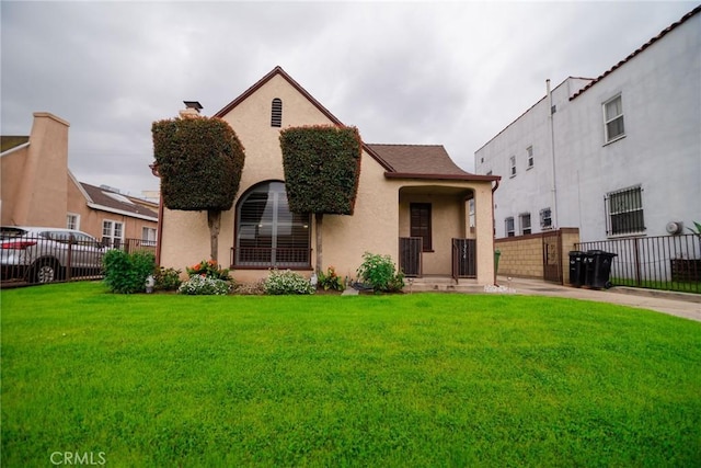 view of front facade featuring stucco siding, a front yard, and fence