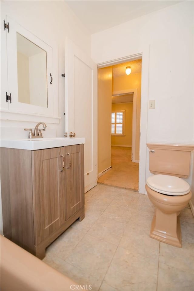 half bathroom featuring tile patterned floors, toilet, and vanity