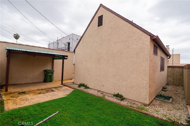 exterior space with a yard, a patio area, fence, and stucco siding