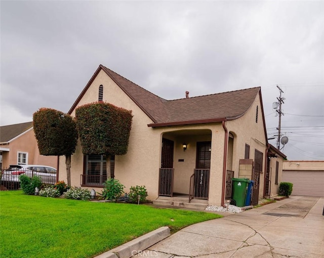 view of front facade featuring stucco siding, an outbuilding, a front yard, and fence