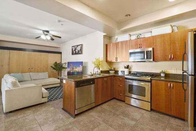 kitchen featuring a ceiling fan, a peninsula, a sink, stainless steel appliances, and open floor plan