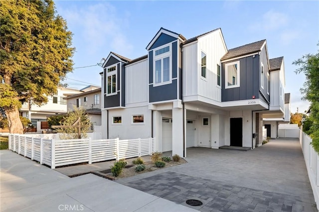 multi unit property with fence, driveway, an attached garage, stucco siding, and board and batten siding