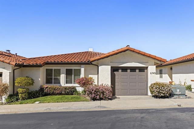 mediterranean / spanish home with a tile roof, a garage, and stucco siding