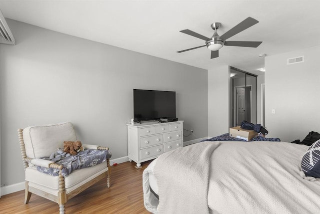 bedroom with ceiling fan, wood finished floors, visible vents, and baseboards