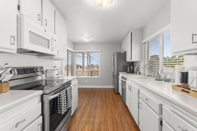 kitchen featuring white cabinets, appliances with stainless steel finishes, light countertops, and a sink