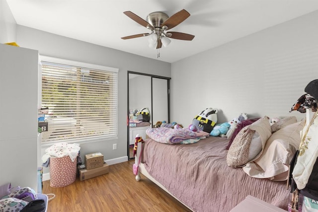 bedroom with ceiling fan, a closet, baseboards, and wood finished floors