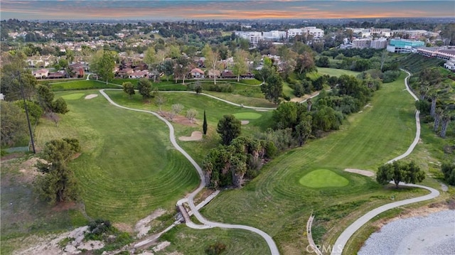 aerial view at dusk featuring view of golf course