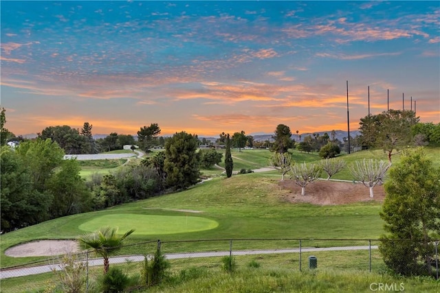 view of community with golf course view, a yard, and fence