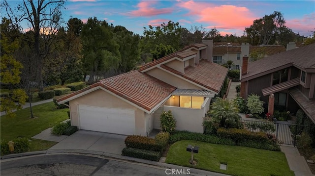 view of front of home featuring fence, a tile roof, stucco siding, a garage, and driveway