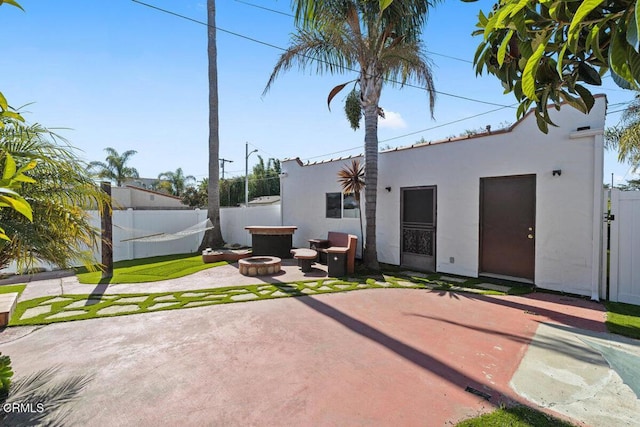 back of property featuring stucco siding, fence, a fire pit, and a patio area