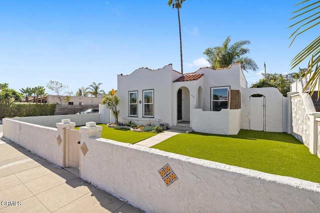 mediterranean / spanish-style house featuring a fenced front yard, stucco siding, a tile roof, and a gate