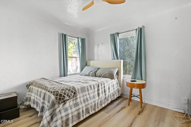 bedroom with ceiling fan, baseboards, a textured wall, and wood finished floors