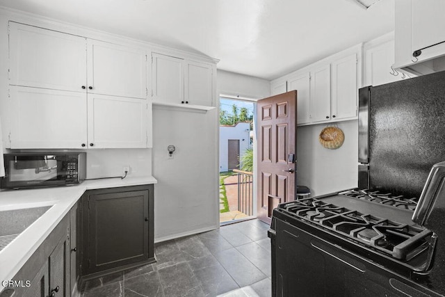 kitchen with baseboards, a sink, black appliances, white cabinets, and light countertops