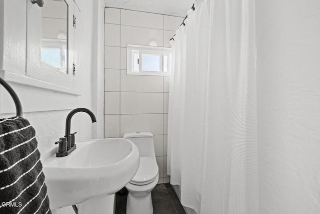 bathroom featuring a sink, curtained shower, toilet, and tile walls