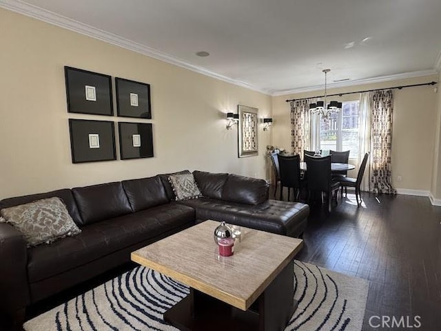 living area featuring baseboards, a notable chandelier, ornamental molding, and dark wood-style flooring