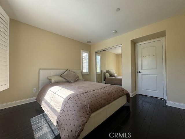 bedroom featuring a closet, baseboards, and dark wood-style floors