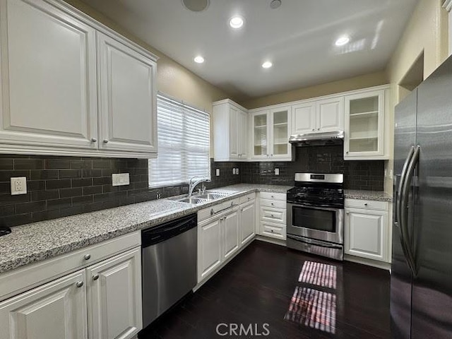 kitchen with under cabinet range hood, white cabinets, appliances with stainless steel finishes, and a sink