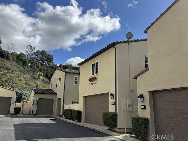 mediterranean / spanish home with stucco siding, a garage, and a tile roof