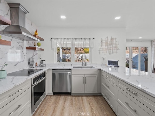 kitchen with open shelves, a sink, light wood-style floors, appliances with stainless steel finishes, and exhaust hood