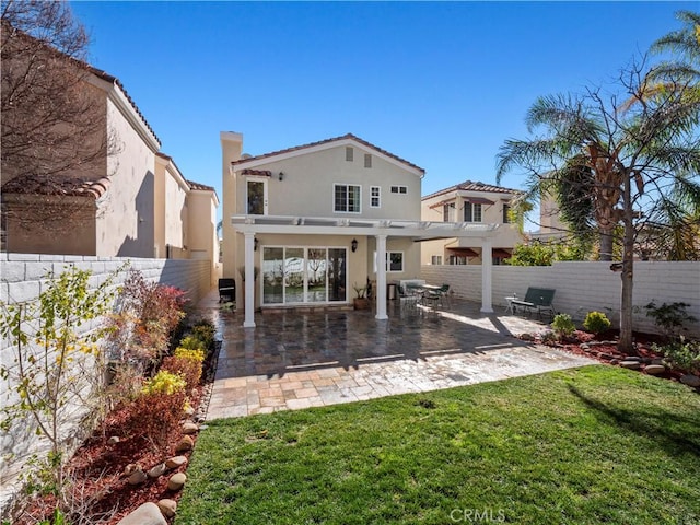 rear view of house with stucco siding, a lawn, a fenced backyard, and a pergola