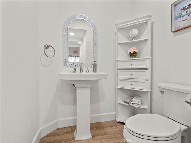 half bathroom featuring baseboards, toilet, and wood finished floors