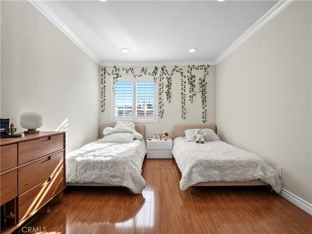 bedroom with crown molding, wood finished floors, and baseboards