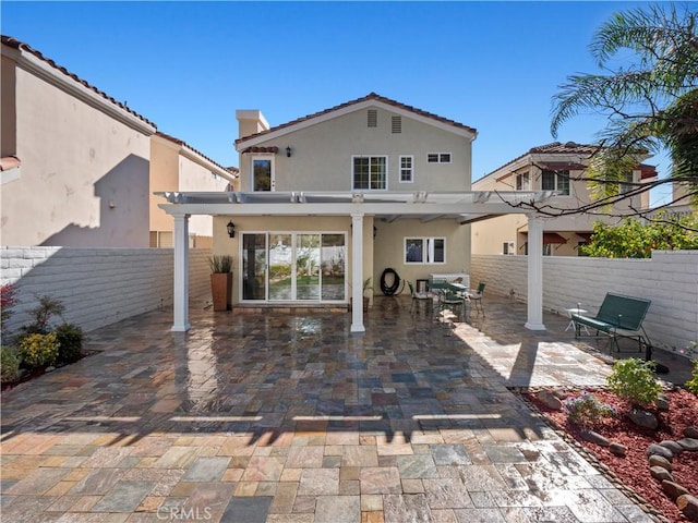 rear view of house featuring stucco siding, a patio, a pergola, and a fenced backyard