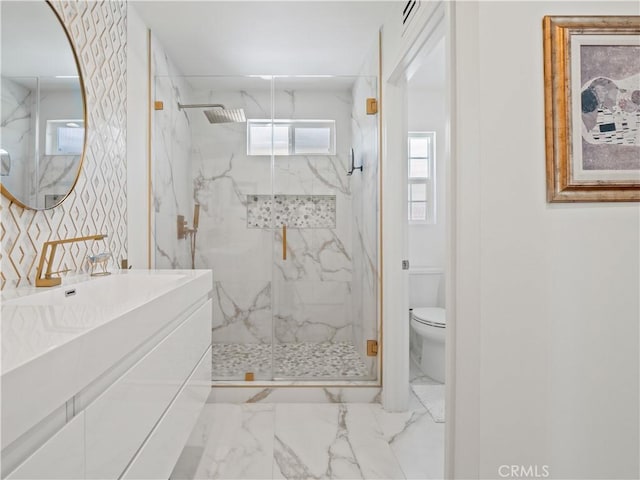 bathroom with a marble finish shower, toilet, marble finish floor, and vanity